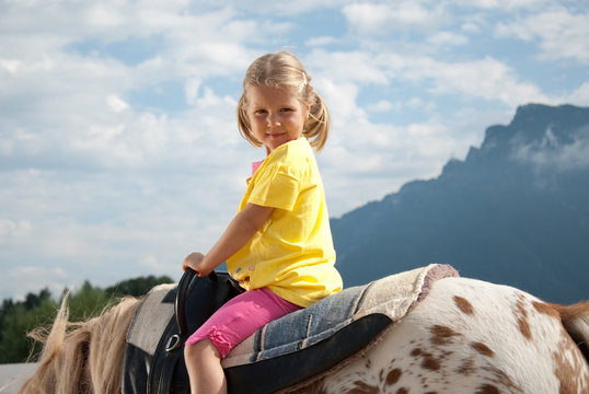 m&auml;dchen sitzt auf pony im freien