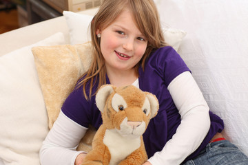 Little girl with toy tiger on sofa