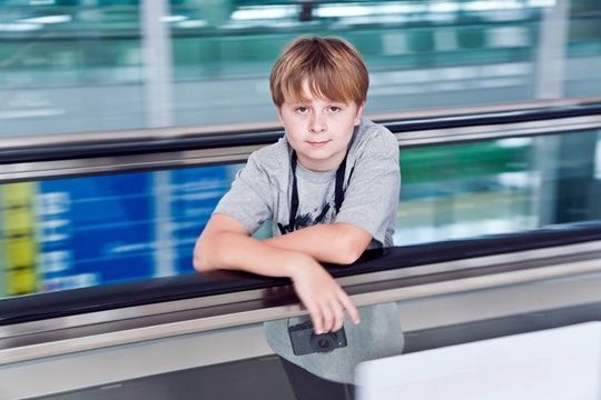 boy in  departure hall  in the Airport  on a moving staircase