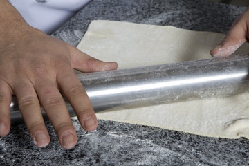 Spreading out cookie dough with rolling pin. Preparing pastry
