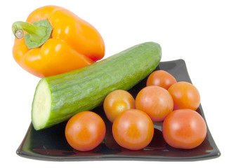 pepper, tomatoes and cucumber on black plate