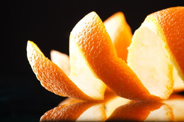 Spiral orange peel reflecting on black background.