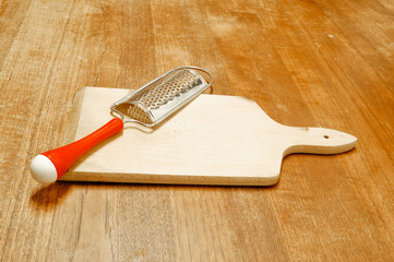 Râpe à fromage et planche posées sur une table en bois