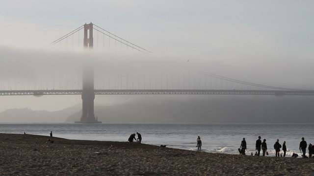 Golden gate bridge with fog and people on a sandy beach