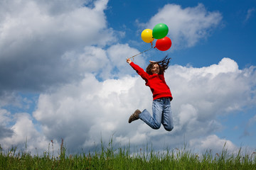 Girl holding balloons jumping outdoor