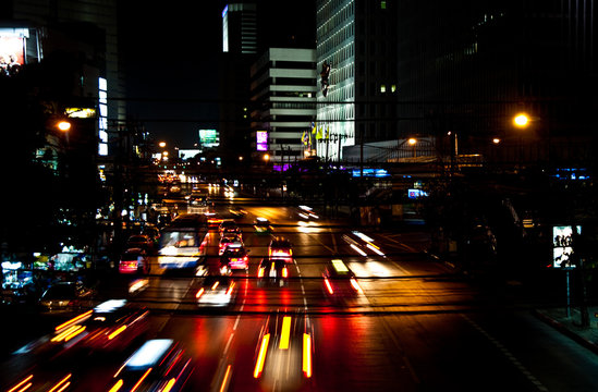 cars by night on a main road in Bangkok with lights on