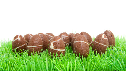 chocolate easter eggs in grass over white background