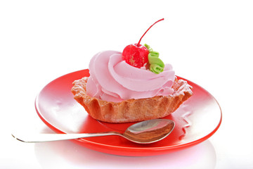 Pink cheesecake with maraschino cherry on the plate