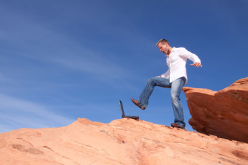 Obraz premium Angrry businessman kicking his laptop