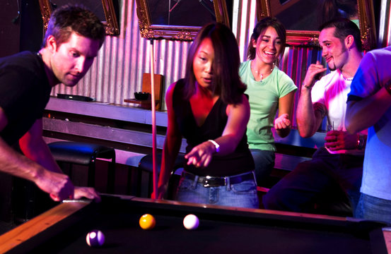 Young adults at a nightclub playing pool