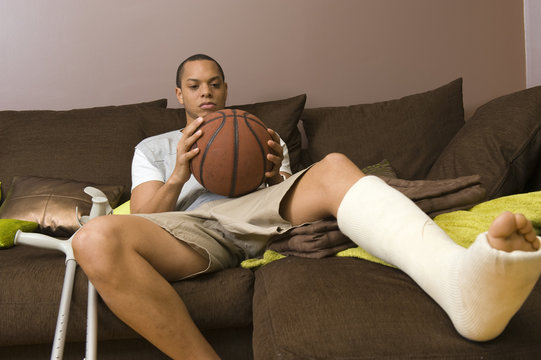 Homme pied platré regarde une bal de basket