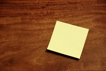 Yellow sticky memo note on wooden background
