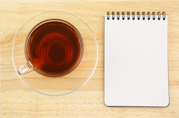 Notebook and tea cup on wooden background