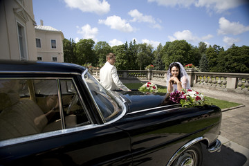 Vintage Wedding Car Decorated with Flowers and bride with groom