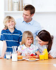 Obraz na płótnie Canvas Jolly family eating breakfast in the kitchen