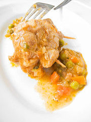 Meat roulade with vegetable soup on white dish.