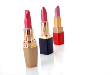 three colored lipsticks on white background