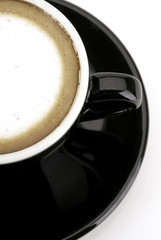 Espresso macchiato in black coffee cup shot in half