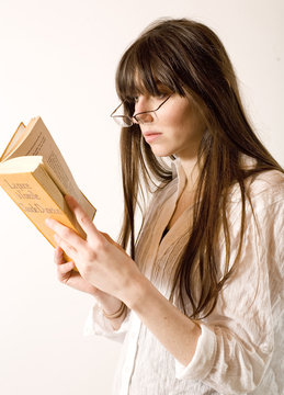jeune femme lit en faisant loupe avec ses lunettes