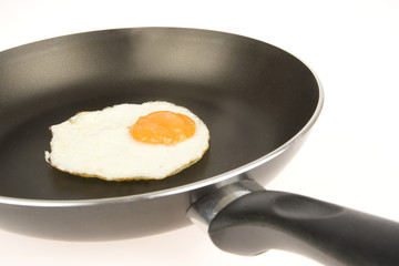 fried egg in pan on white