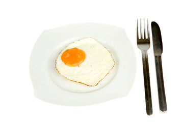 an egg on a plate with fork and knife