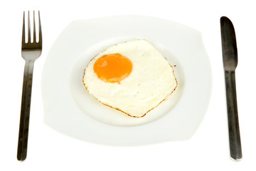 egg on a plate with a fork and knife