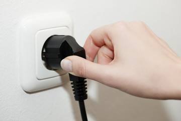 Stecker aus der elektrischen Steckdose ziehen