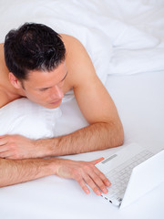 Obraz na płótnie Canvas e-mail checkng man in bed