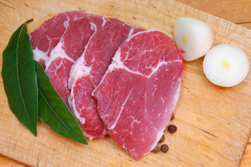 Raw pork chops on the cutting wooden board.