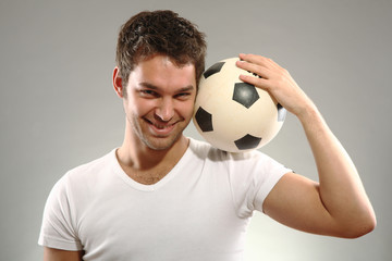 junger mann hält einen Fussball auf seiner Schulter