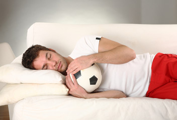junger mann schläft mit seinem fussball sieger