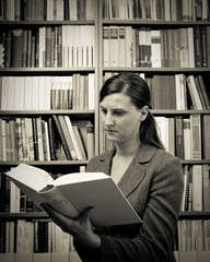 junge Frau im Business mit Buch in der Hand in Bibliothek
