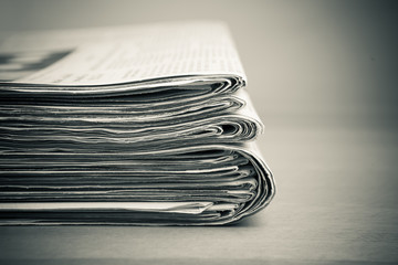 Stapel Zeitungen auf Holztisch, monochrom