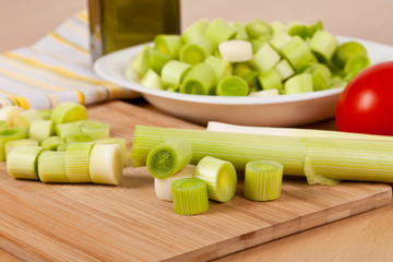 Fresh chopped leeks on a wooden board with red tomatoes