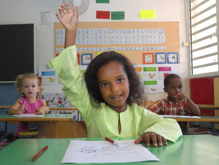 Fillette levant son doigt dans une classe.