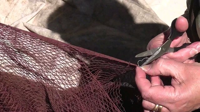 MUJER REPARANDO LAS REDES DE PESCA