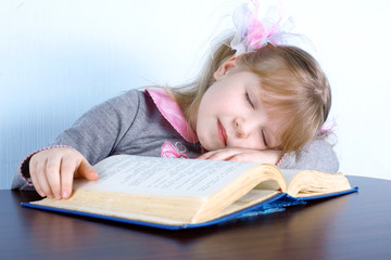 girl sleeping on book at table