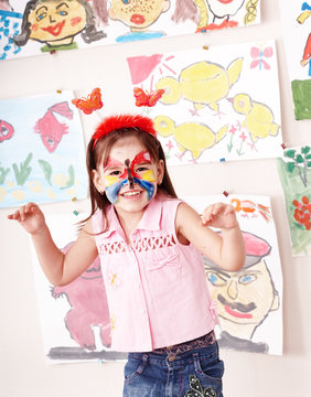 Child with paint of face in play room.