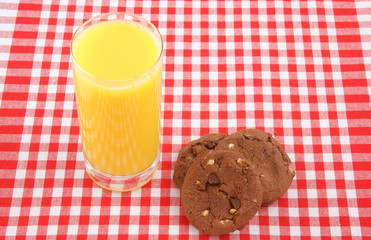 Chocolate cookies and glass of orange juice on tablecloth