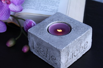 Teelicht vor aufgeschlagener Bibel und Orchidee