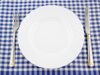 Waiting for meal, empty plate with knife and fork on tablecloth