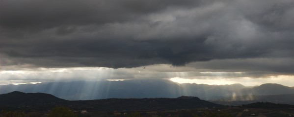 Fototapeta premium Sun beams bursting through very dark threatening clouds