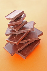 Stack Of Dark Chocolate Pieces,  Over Orange Background