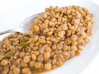 Lentil soup with spoon on white dish.