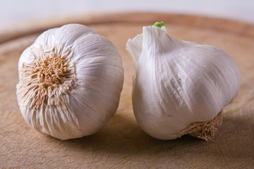 Two Garlic heads on a wood cutting board