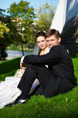 Beautiful bride and groom sit on the grass