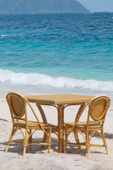 a table and two chairs at the shore