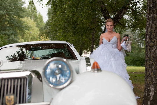 Bride near vintage retro car before wedding ceremony