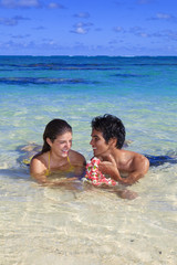 young couple frolic in the tropical water with a flower lei