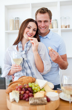 Cheerful couple drinking white wine and eating cheese